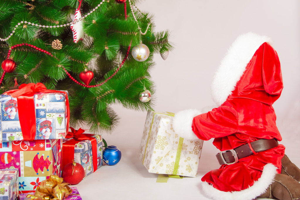 Bebé en traje de Santa en el árbol de Navidad con regalos
 - Foto, Imagen
