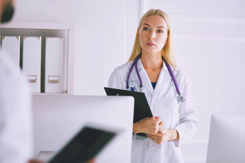 Женщина-врач стоит с папкой в больнице. - Фото, изображение