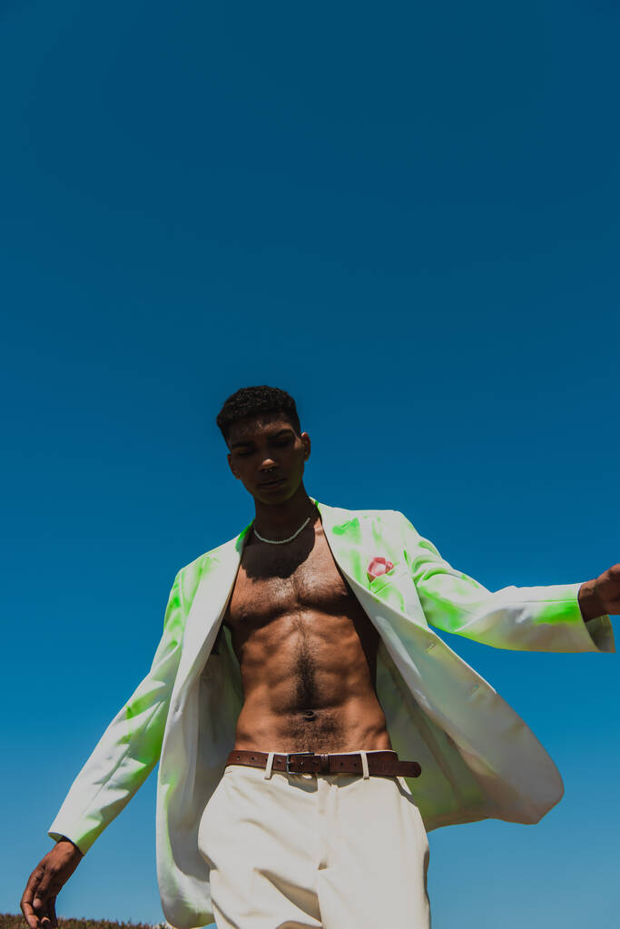 low angle view of african american man in white and green blazer under cloudless sky - Foto, imagen