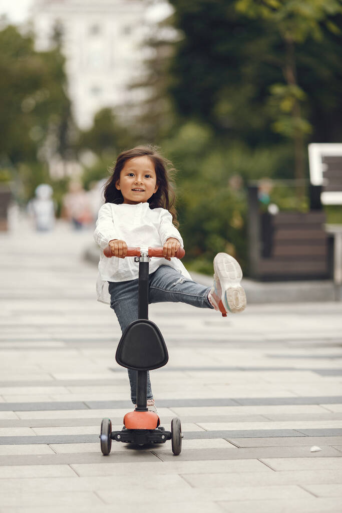 Child on kick scooter in park. Kids learn to skate roller board. Little girl skating on sunny summer day. - Φωτογραφία, εικόνα