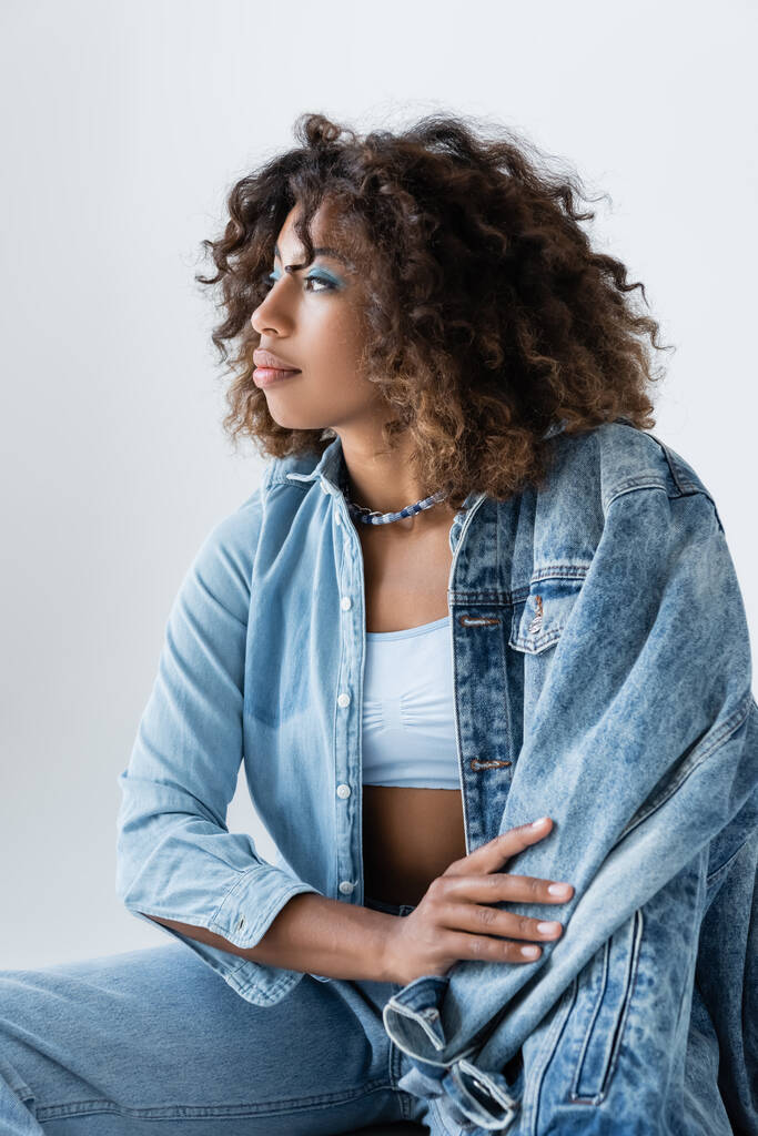 trendy african american woman with wavy hair looking away isolated on grey - Fotografie, Obrázek