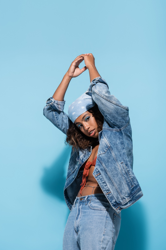african american woman in denim clothes posing with raised hands and looking at camera on blue background - Φωτογραφία, εικόνα