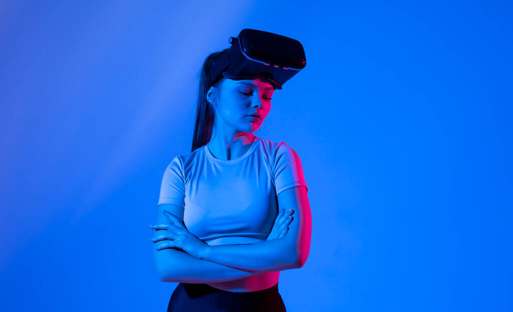 Portrait of young woman with a glasses of virtual reality in neon light. VR, augmented reality, science, future technology concept. Futuristic 3d glasses with virtual projection - Foto, Imagen