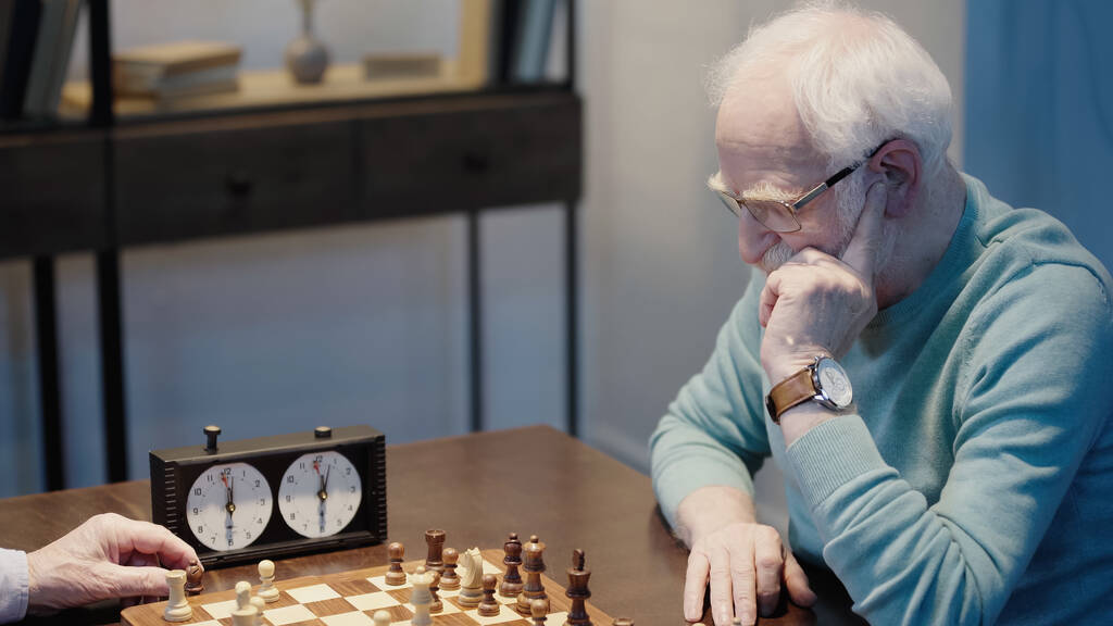 сіра волохата людина в окулярах думає біля шахівниці і старшого друга
 - Фото, зображення