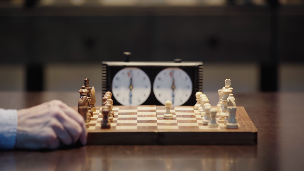 selective focus of chessboard near cropped man and blurred chess clock - Fotoğraf, Görsel