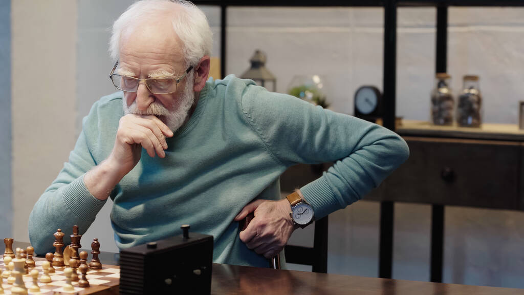 senior man in eyeglasses thinking near chessboard at home - Valokuva, kuva