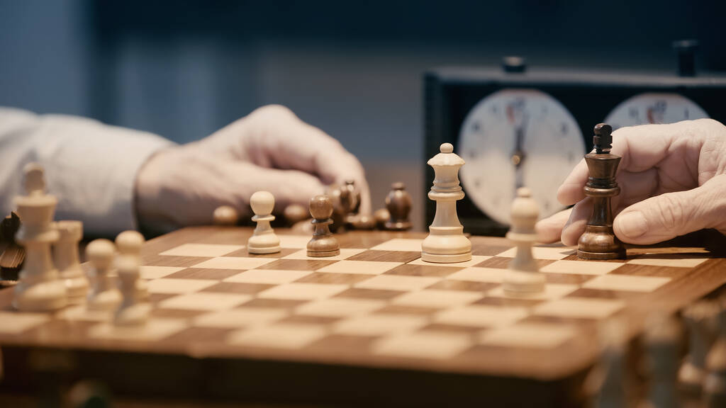 partial view of senior men playing chess on blurred chessboard - Foto, imagen