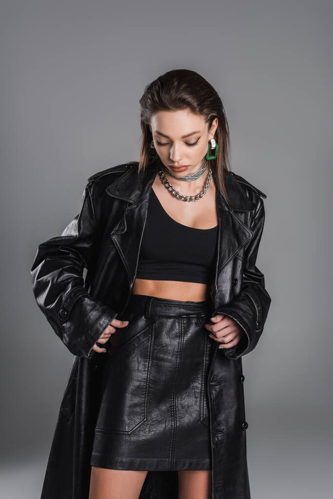 fashionable woman in black crop top and leather clothing isolated on grey - Fotografie, Obrázek