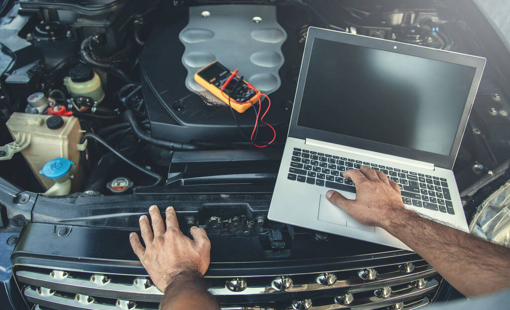 man to repair car with hand computer - Foto, imagen