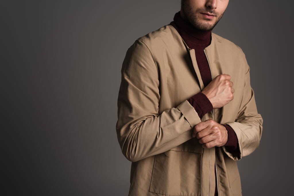 Cropped view of man adjusting sleeve of autumn jacket isolated on grey  - Foto, Imagen
