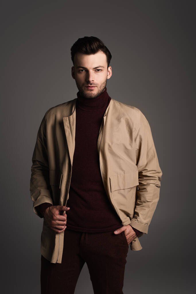 Stylish brunette man in jacket posing isolated on grey  - 写真・画像
