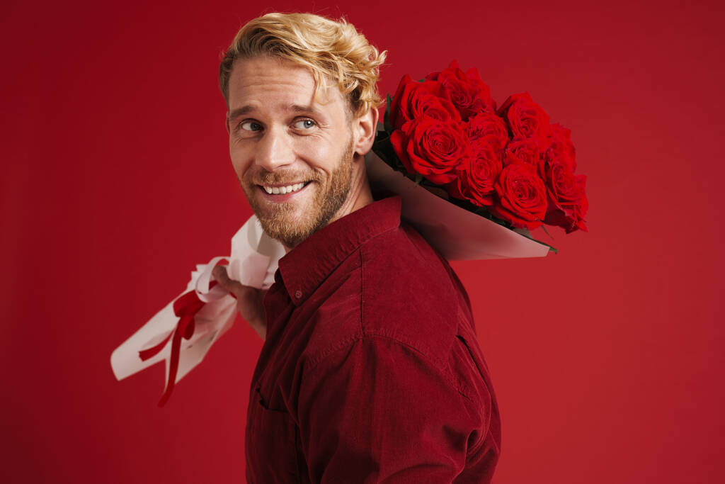 White bearded man smiling while posing with roses isolated over red wall - Fotografie, Obrázek
