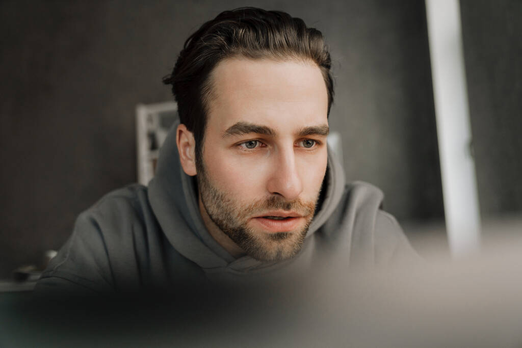 Young beard man working with laptop while sitting at desk in office - Photo, image