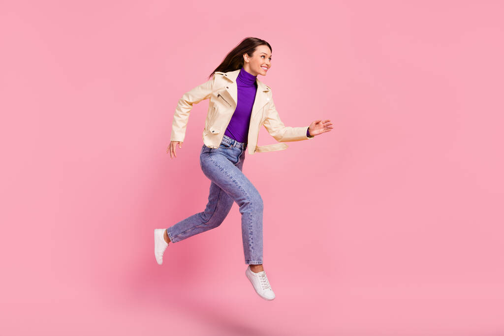 Фотографія повного тіла красивої брюнетки леді біжить в куртці джинси кросівки ізольовані на рожевому кольоровому фоні
. - Фото, зображення