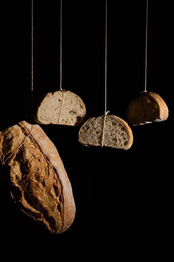 A closeup of hanging bread slices with a black background - Photo, Image