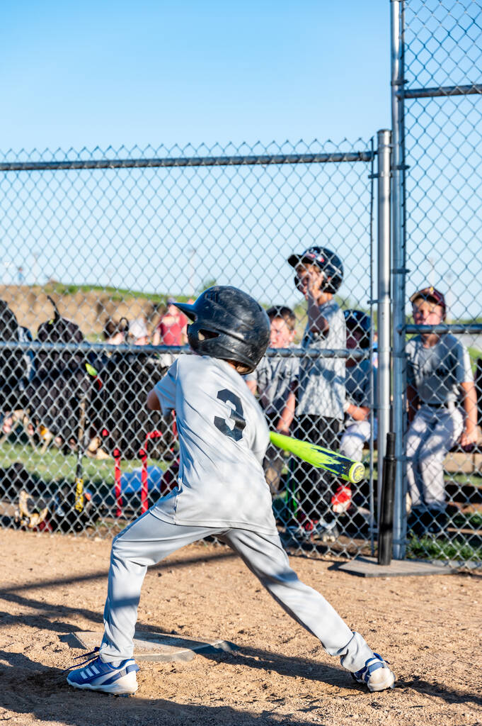 Young boy taking a swing at a baseball with the team defocused in the background.. High quality photo - Foto, imagen