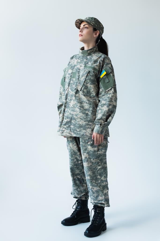Full length of servicewoman in uniform with ukrainian flag on grey background - Zdjęcie, obraz