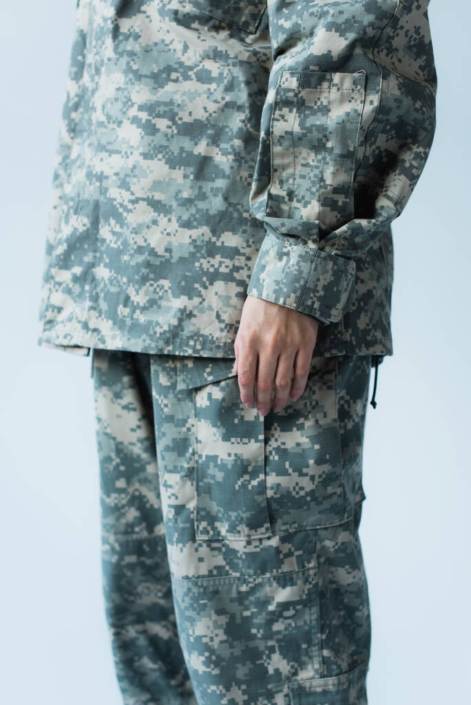 Cropped view of servicewoman in camouflage uniform standing isolated on grey  - Фото, изображение