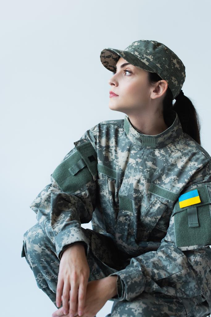 Widok z boku służącej w mundurze z ukraińską flagą na szewronie odizolowany na szarości  - Zdjęcie, obraz
