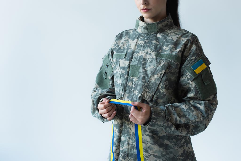 Cropped view of soldier in uniform holding blue and yellow ribbon isolated on grey  - Fotoğraf, Görsel