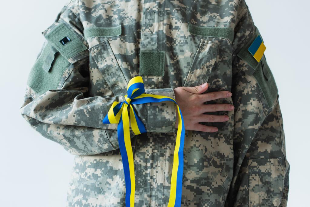 Levágott kilátás katona ukrán zászló és kék és sárga szalag kézzel elszigetelt szürke  - Fotó, kép