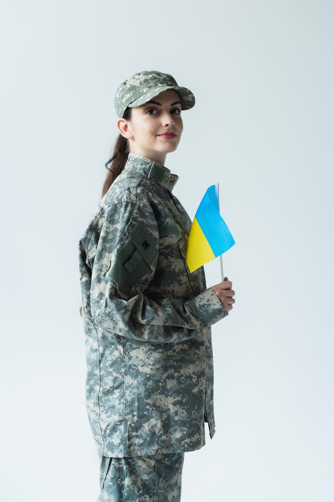 Молода служниця тримає прапор українки ізольований на сірому  - Фото, зображення
