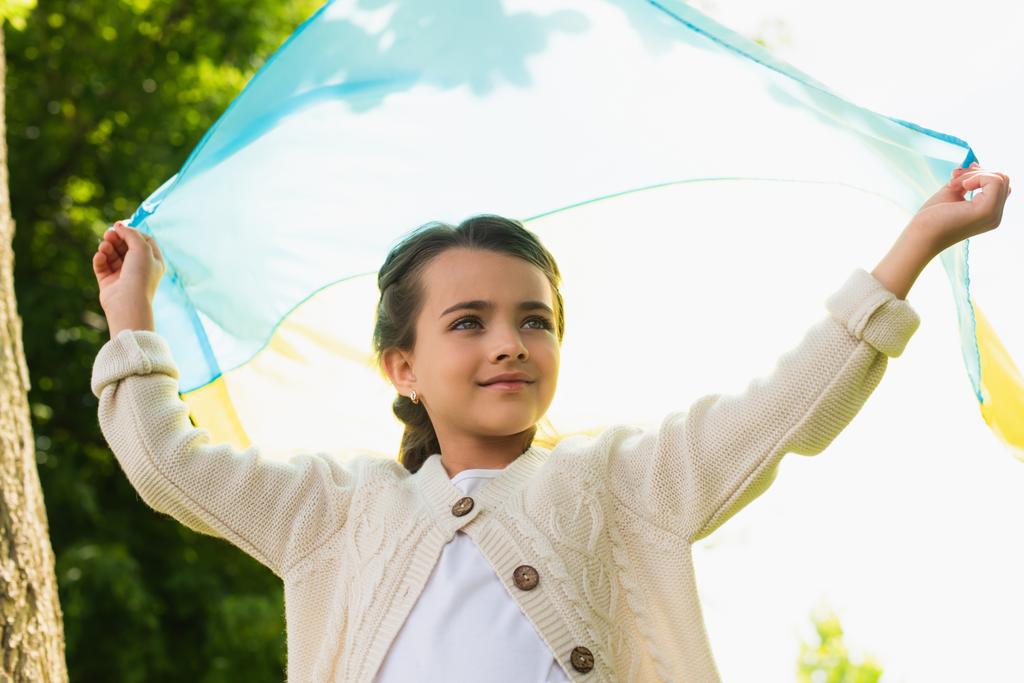 patriotic girl standing with ukrainian flag outdoors - Foto, Imagen