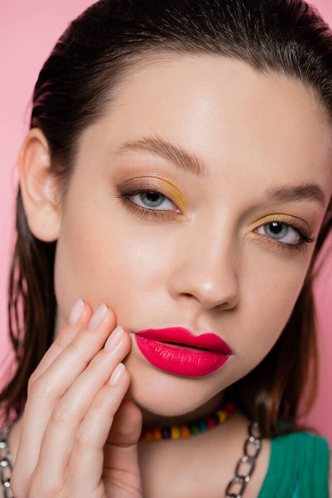 close up view of young brunette woman with bright makeup looking at camera isolated on pink  - Fotó, kép