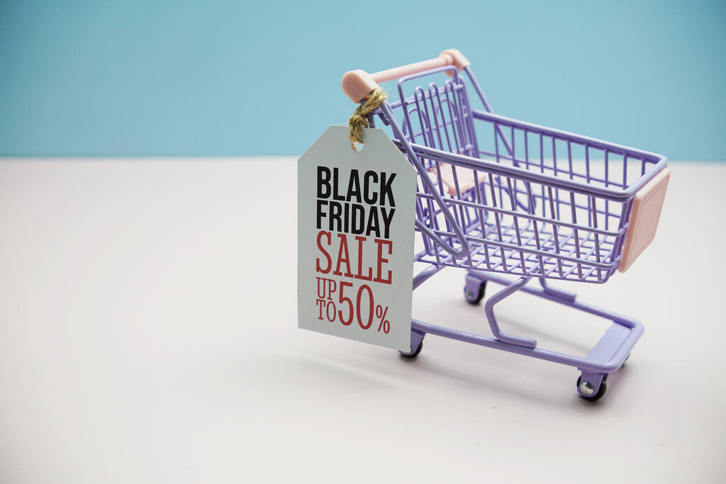 Black Friday Salee 50%  text message on price tax with shoppint trolley cart on blue andp pink background - Foto, immagini