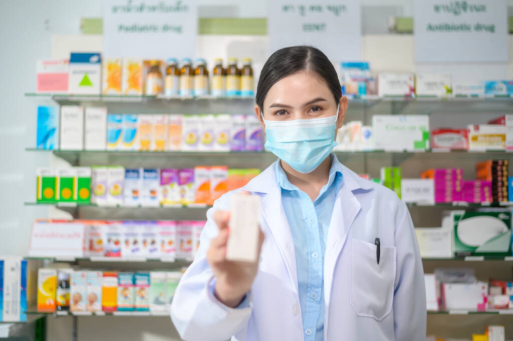 A Portrait of female pharmacist wearing face mask in a modern pharmacy drugstore. - Fotografie, Obrázek