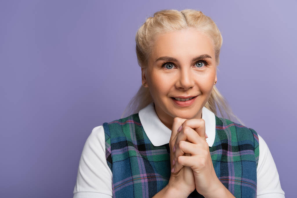 Portrait of blonde student with clenched hands looking at camera isolated on purple  - Foto, afbeelding