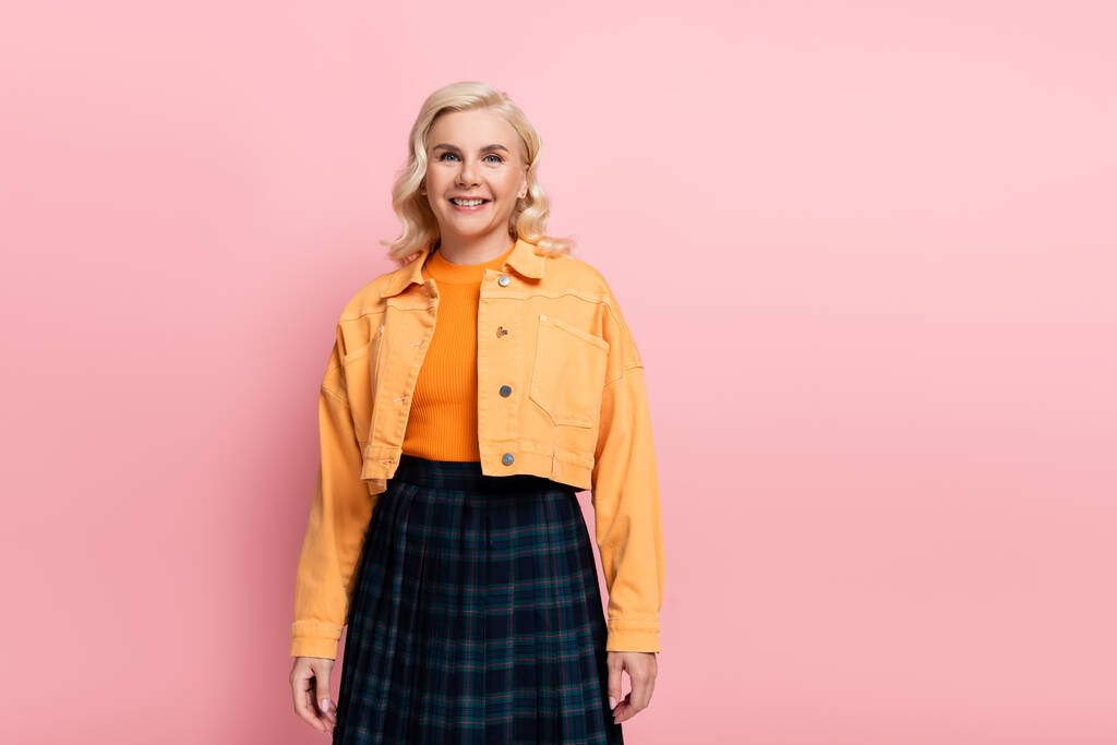 Positive woman in orange jacket looking at camera isolated on pink  - Foto, Imagem