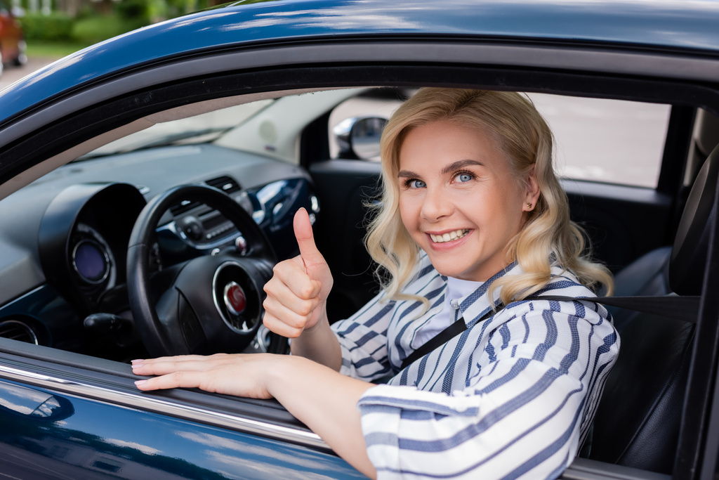 Smiling driver showing like during driving course in car  - Фото, изображение
