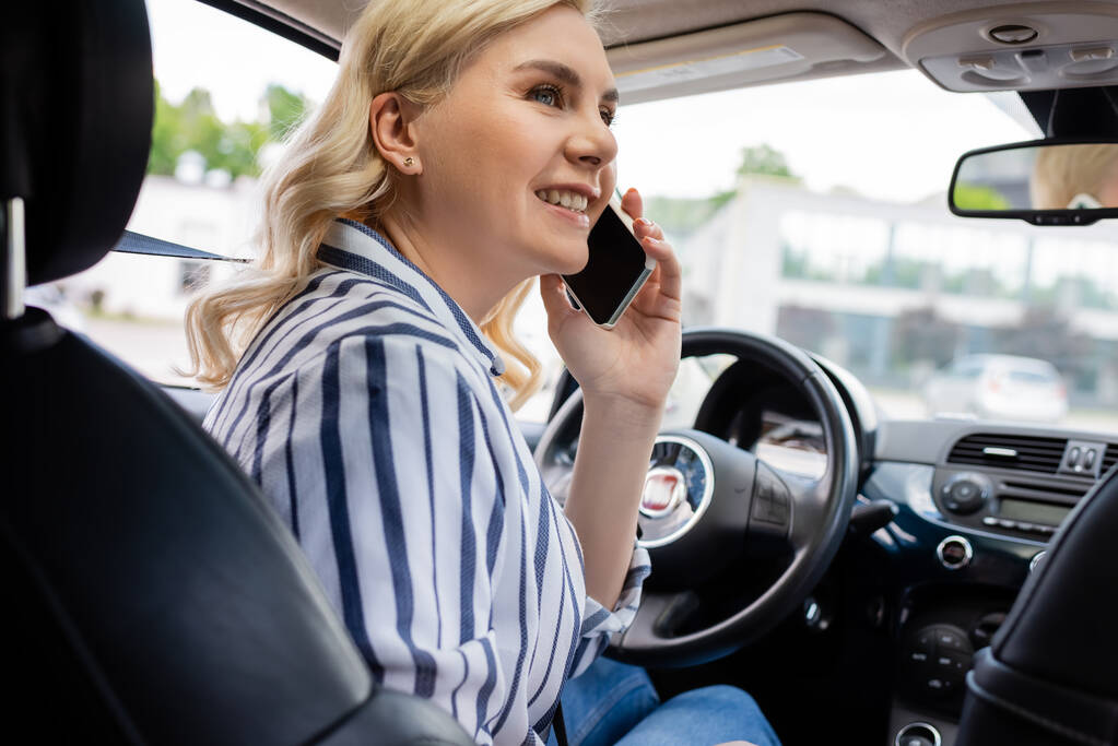 Smiling woman talking on smartphone on driving seat in car  - Fotografie, Obrázek