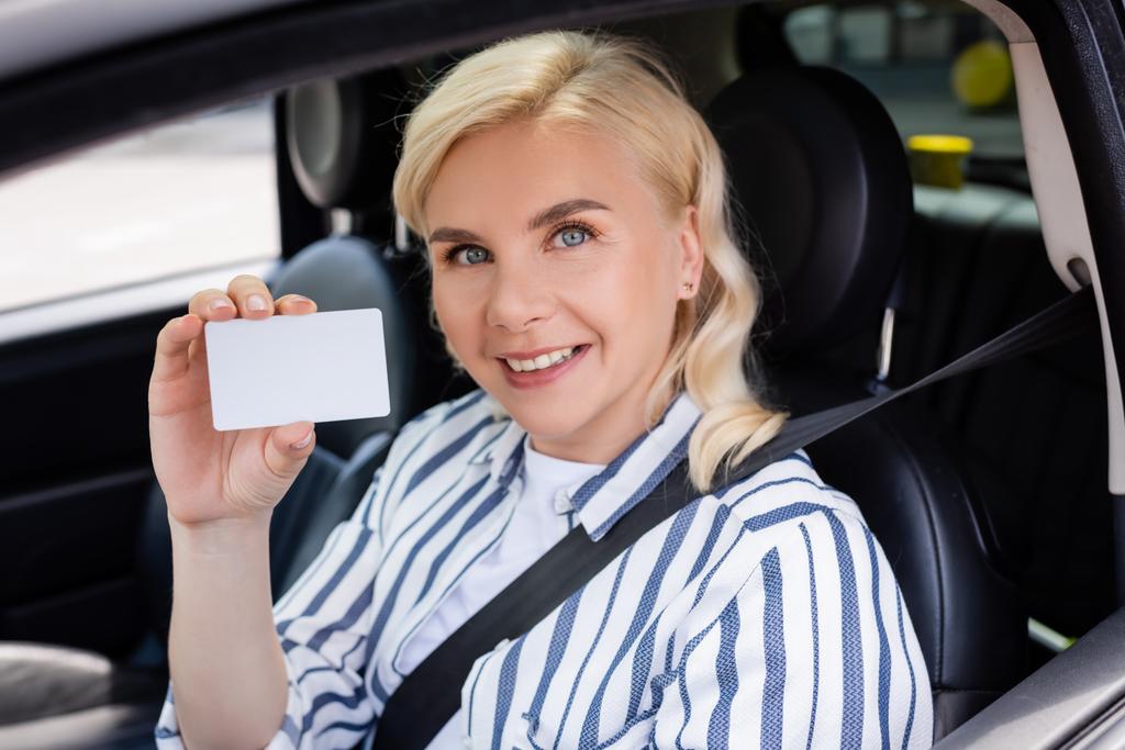Cheerful woman holding driver license in auto  - Foto, immagini