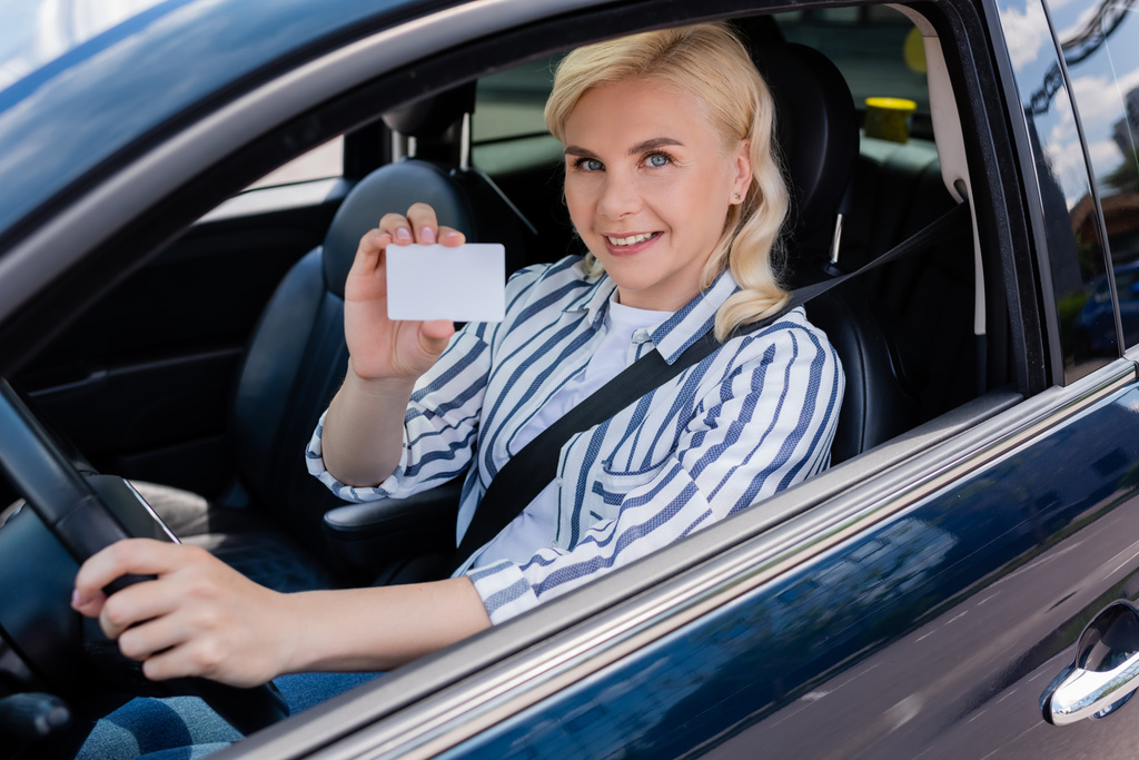 Happy driver holding license and looking at camera in auto  - Photo, image