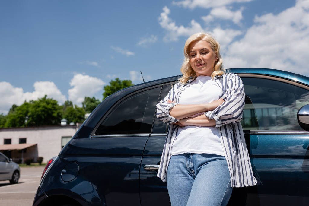 Smiling woman in shirt crossing arms while standing near car  - Photo, image
