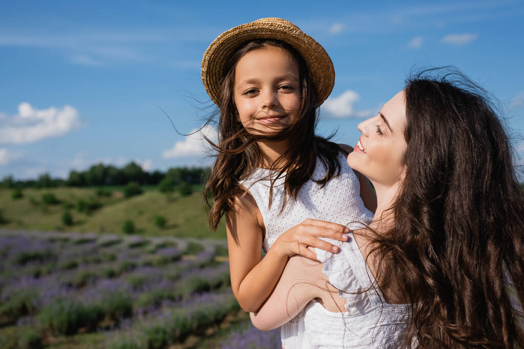 happy woman holding daughter smiling at camera outdoors - Foto, Bild