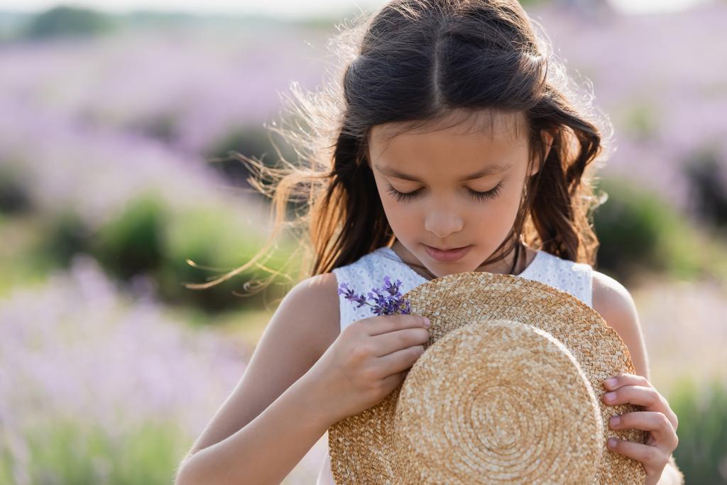 girl with long hair decorating straw hat with lavender flowers - Photo, image
