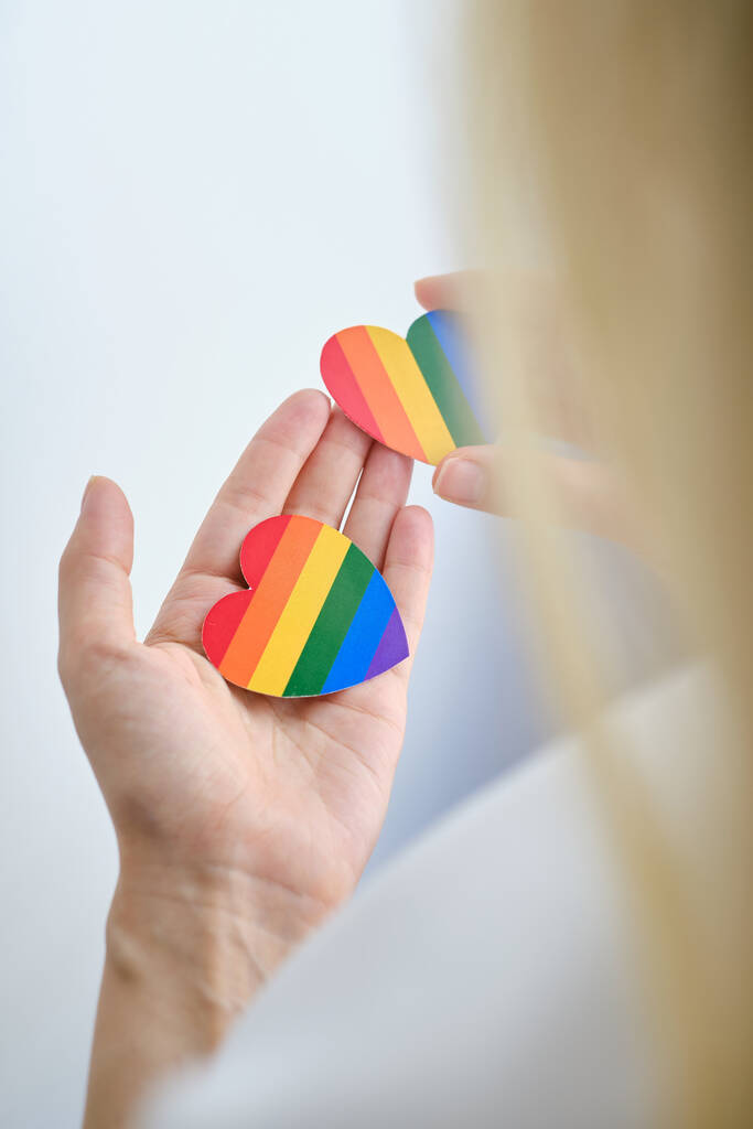 Rainbow heart from paper in woman hands in white t-shirt. LGBT flag. LGBTQIA Pride Month in June. Lesbian Gay Bisexual Transgender. Gender equality. Human rights and tolerance. Rainbow flag - Foto, Imagen