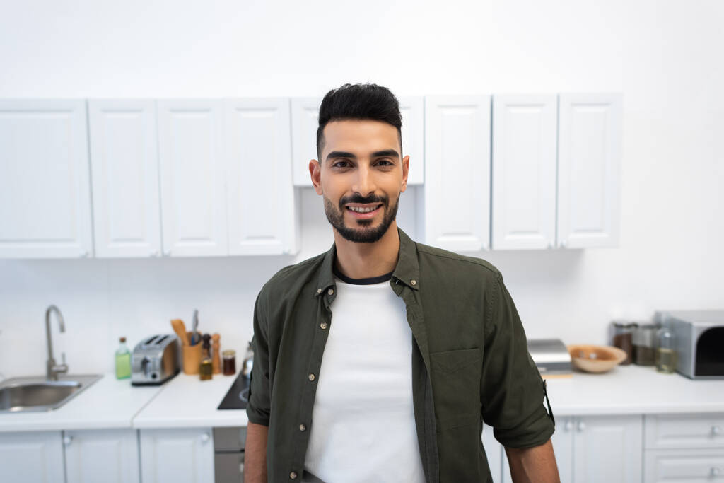 Smiling arabian man looking at camera in kitchen  - Photo, image
