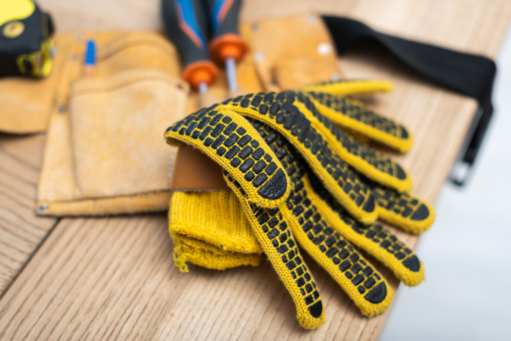Close up view of gloves near blurred tool belt on table  - Foto, afbeelding