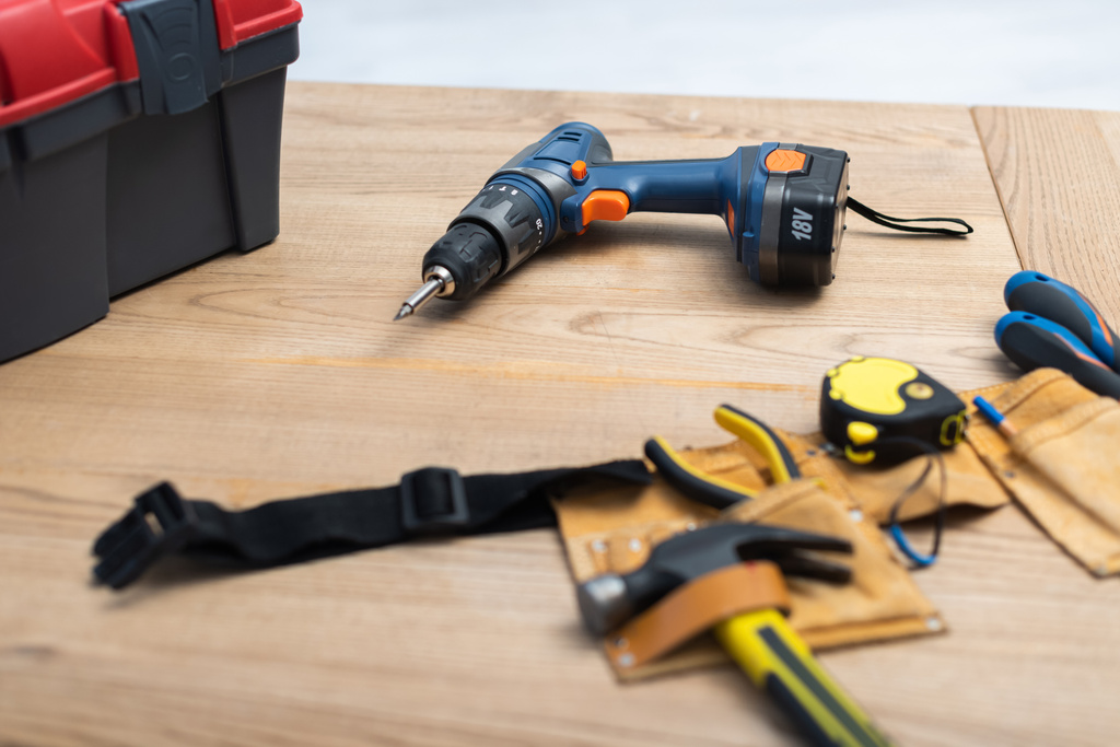 Electric screwdriver near tool belt on table at home  - Foto, afbeelding