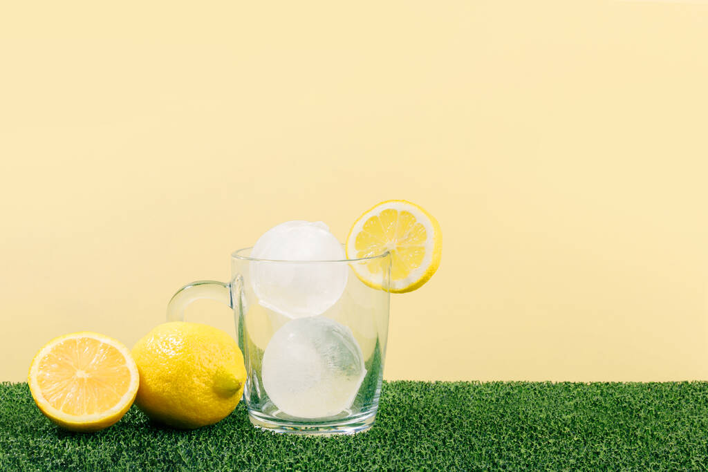creative summer photo_water cup and ice, yellow background - Photo, Image
