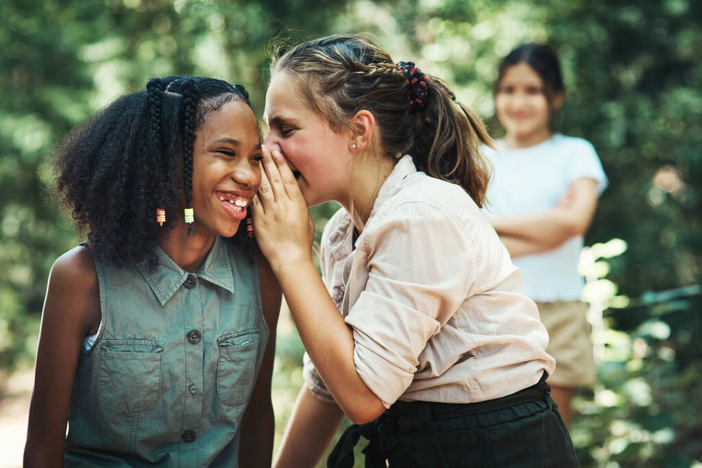 Beware the danger of bullying. two teenage girls gossiping about their friend at summer camp - Photo, Image