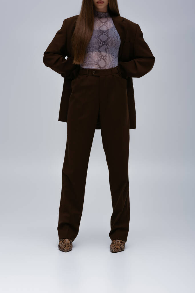 cropped view of teenage model in brown high-quality suit posing on grey - Fotó, kép