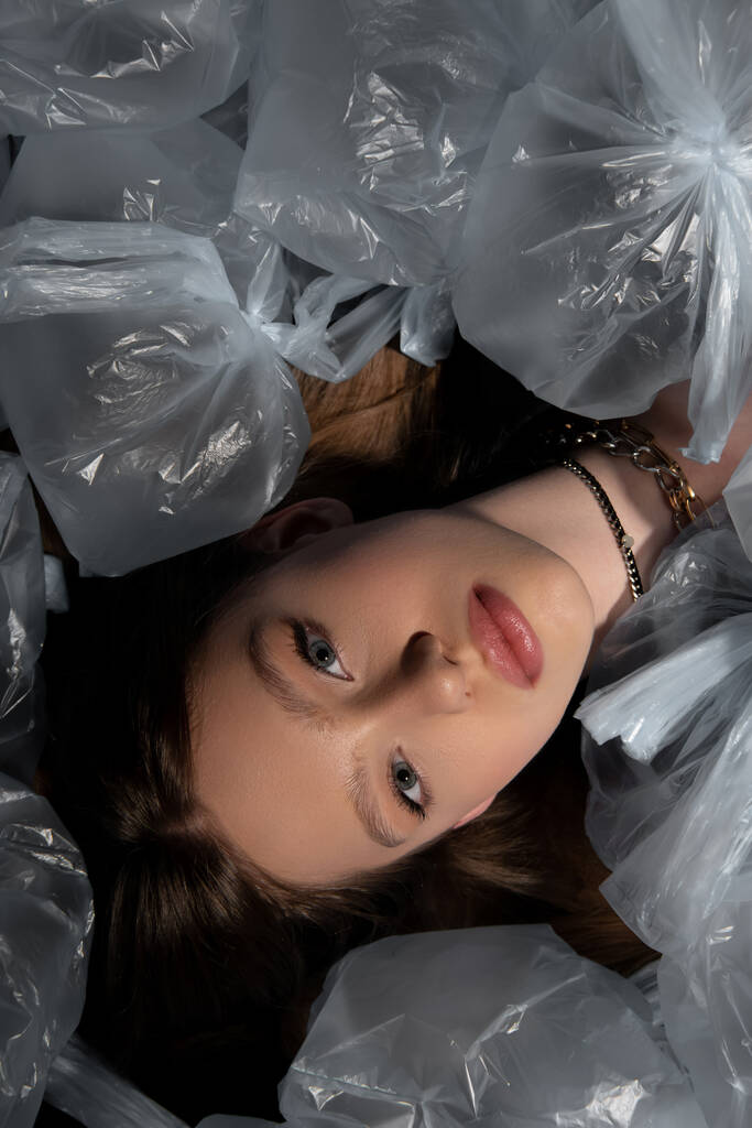 top view of brunette model lying around plastic bags, recycle fashion concept - Foto, immagini