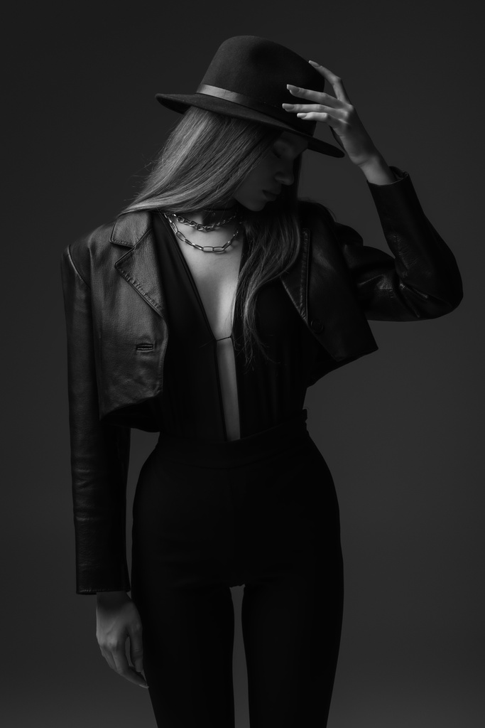 monochrome photo of teenage model adjusting fedora hat in studio  - Foto, Imagen