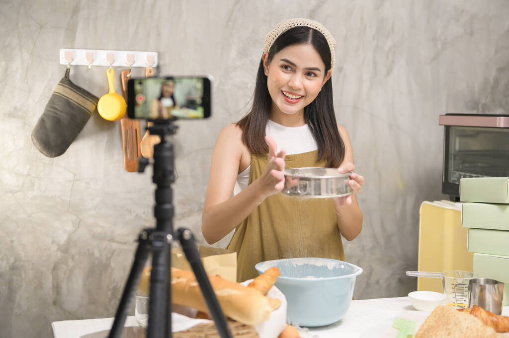 A Beautiful woman is making bakery while live streaming or recording video on social media in her house, coffee shop business concept.  - Foto, imagen