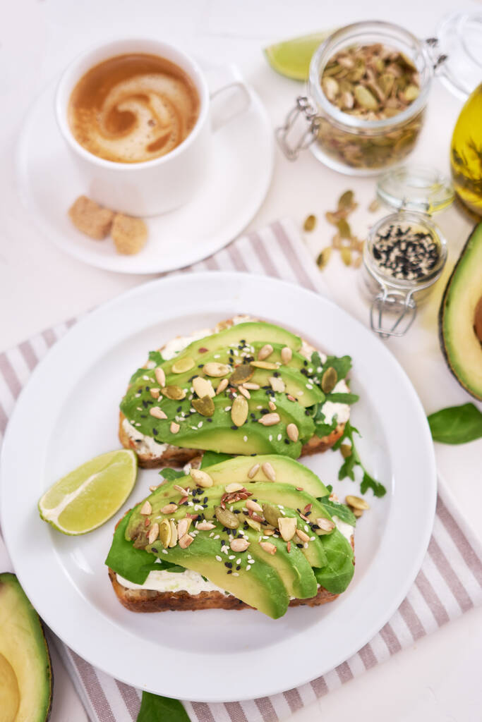 Freshly made Avocado and cream cheese toasts on a white ceramic plate and ingredients. - Photo, image